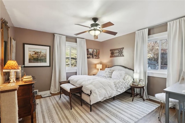 bedroom with light wood-style flooring, a ceiling fan, and baseboards