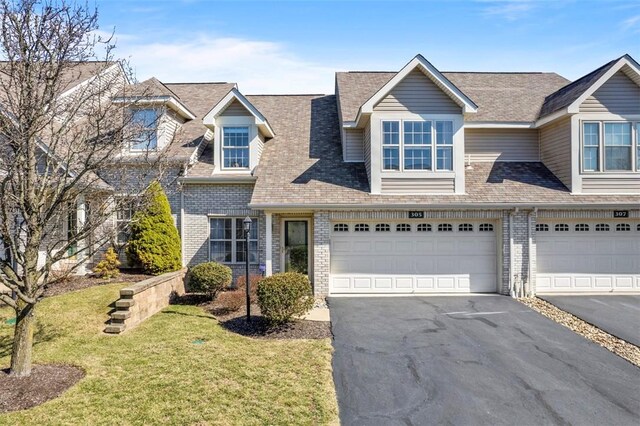 view of front of property with brick siding, an attached garage, a front lawn, roof with shingles, and driveway