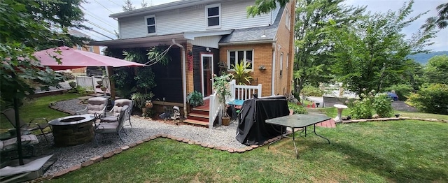 rear view of property with a patio, brick siding, a lawn, and an outdoor fire pit