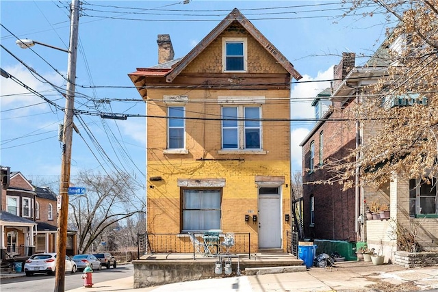 view of front facade featuring brick siding and a chimney