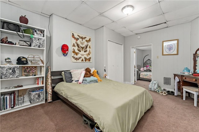 bedroom featuring a drop ceiling and carpet