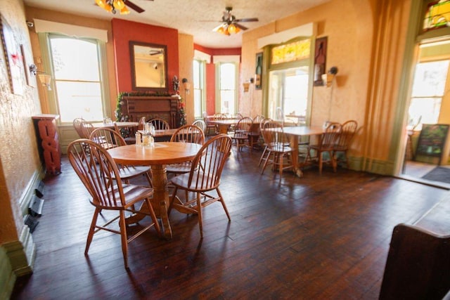 dining space featuring hardwood / wood-style floors, a brick fireplace, and ceiling fan