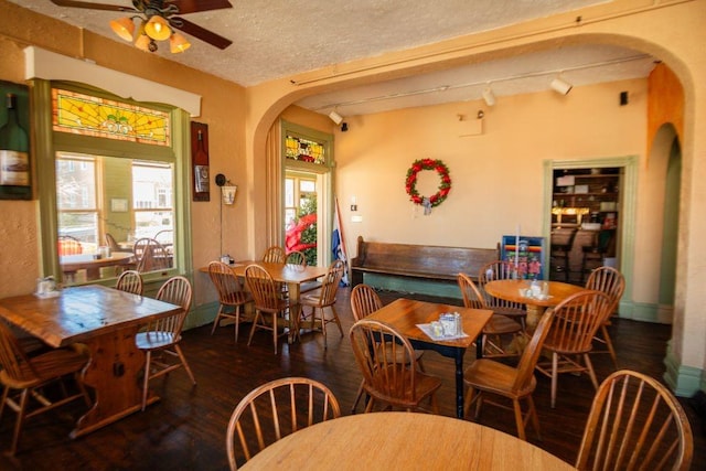 dining area featuring wood finished floors, arched walkways, and a wealth of natural light