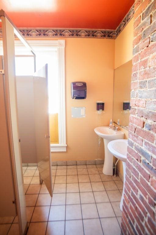 bathroom with tile patterned flooring and brick wall