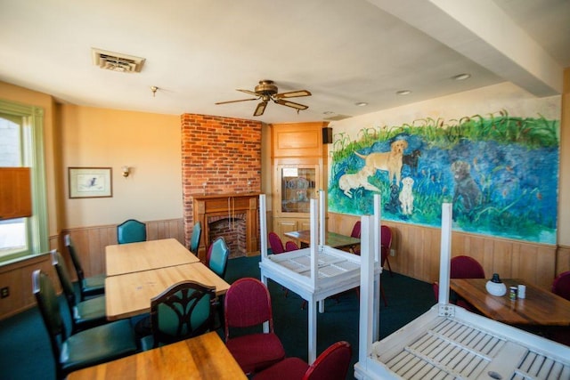 dining space featuring wooden walls, a fireplace, visible vents, and a healthy amount of sunlight