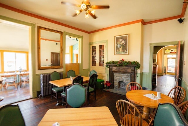 dining room with wood finished floors, crown molding, a fireplace, and a wealth of natural light