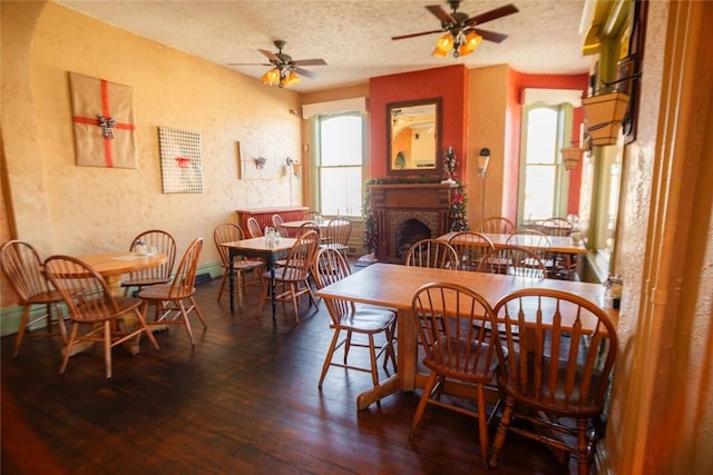 dining space with a textured ceiling, hardwood / wood-style floors, a fireplace, and a textured wall