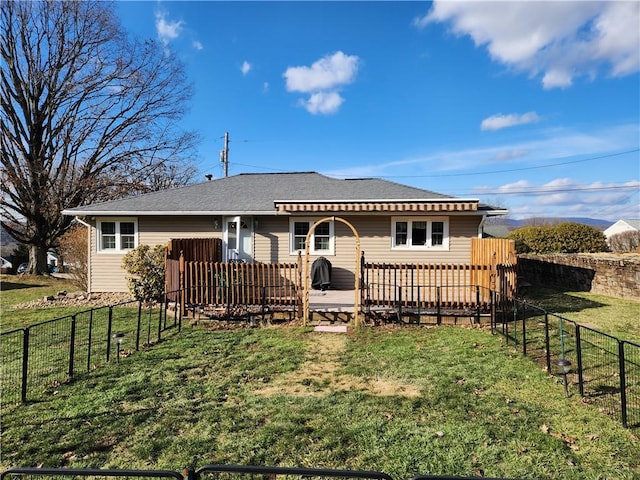 back of property with a deck, a yard, a fenced backyard, and roof with shingles