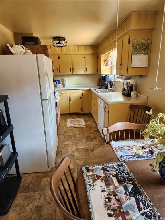 kitchen featuring stone finish floor, white appliances, light countertops, and a sink