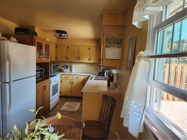 kitchen with a sink, white appliances, and light countertops