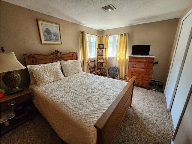 bedroom with light colored carpet, a textured ceiling, and a textured wall