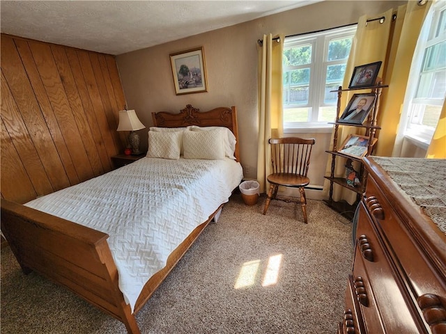 carpeted bedroom featuring wooden walls and a textured ceiling