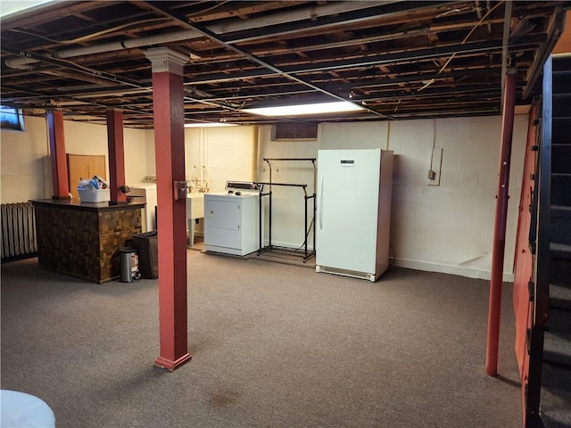 finished basement with washer and clothes dryer, freestanding refrigerator, and a sink