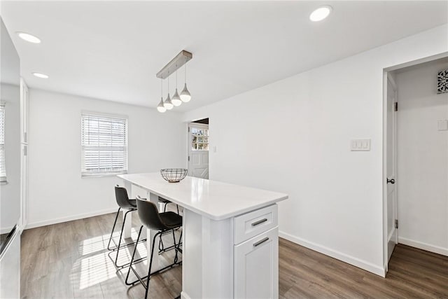 kitchen with baseboards, a breakfast bar, light wood-style flooring, and light countertops