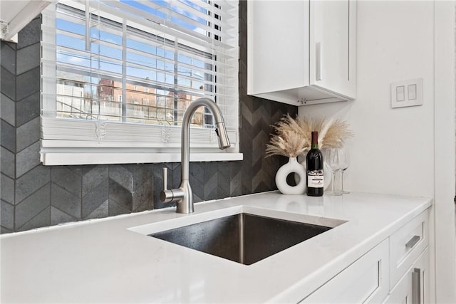 details with tasteful backsplash, white cabinets, light countertops, and a sink