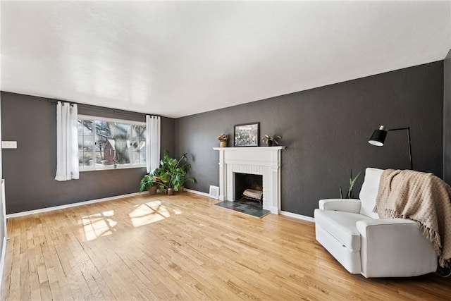 unfurnished living room featuring baseboards, a brick fireplace, and hardwood / wood-style floors