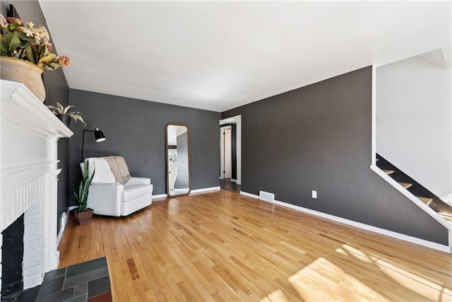 unfurnished living room featuring visible vents, baseboards, a fireplace, wood finished floors, and arched walkways