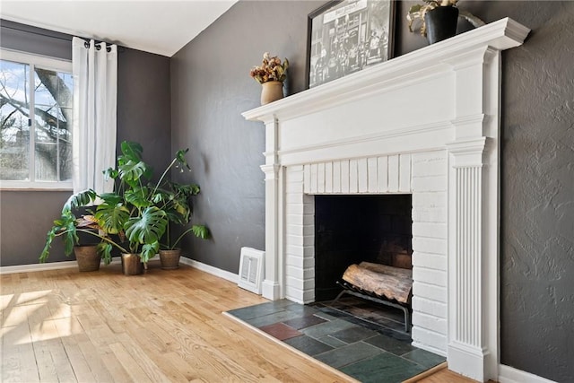 interior space featuring visible vents, baseboards, wood finished floors, and a fireplace