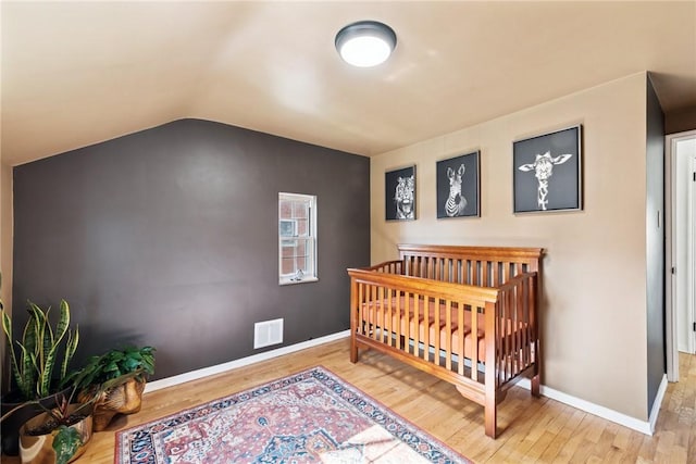 bedroom with visible vents, baseboards, lofted ceiling, and wood finished floors