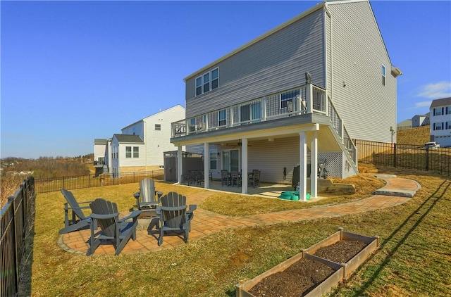 rear view of property featuring a balcony, a garden, a fenced backyard, a patio area, and a lawn