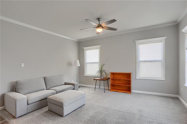 living area with light colored carpet, a ceiling fan, baseboards, and ornamental molding