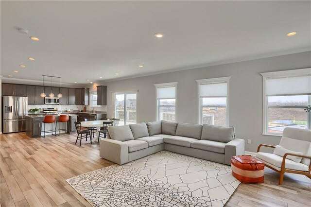 living room with recessed lighting, light wood-type flooring, and ornamental molding