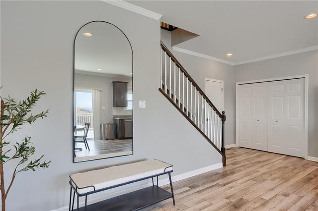 entryway with light wood-type flooring, baseboards, ornamental molding, and stairway