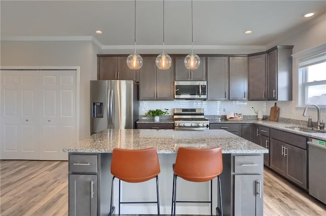 kitchen with a sink, a kitchen island, appliances with stainless steel finishes, and a breakfast bar