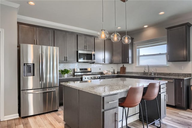 kitchen featuring tasteful backsplash, a kitchen island, light stone counters, appliances with stainless steel finishes, and a sink