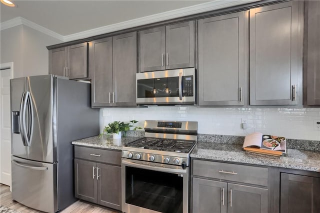 kitchen featuring decorative backsplash, crown molding, light stone countertops, and appliances with stainless steel finishes