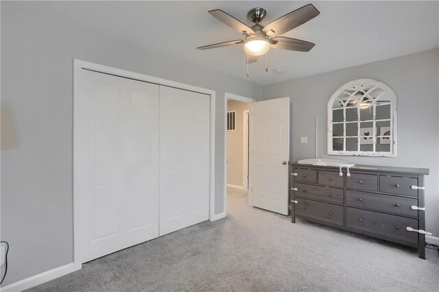 unfurnished bedroom featuring a ceiling fan, baseboards, a closet, and light carpet