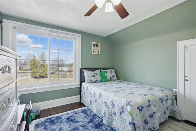 bedroom with a ceiling fan, vaulted ceiling, wood finished floors, and baseboards