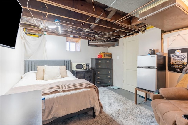 bedroom with concrete floors and freestanding refrigerator