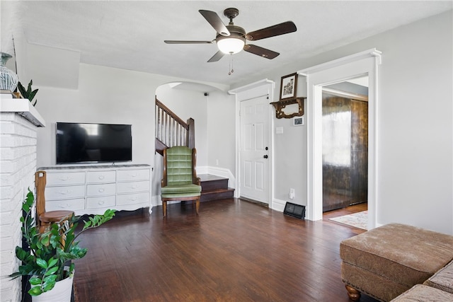 living area with wood finished floors, baseboards, arched walkways, ceiling fan, and stairs