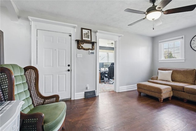 living area featuring a textured ceiling, a ceiling fan, baseboards, and wood finished floors