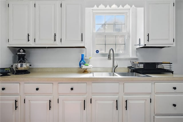 kitchen with a sink, white cabinets, and light countertops