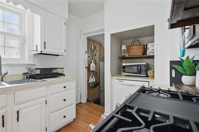 kitchen with light wood finished floors, stainless steel microwave, white cabinets, light countertops, and dishwasher