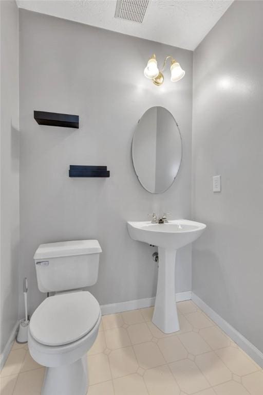 half bath featuring visible vents, toilet, and baseboards