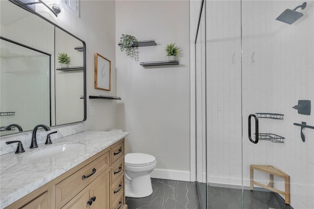 bathroom featuring a shower stall, toilet, vanity, and baseboards