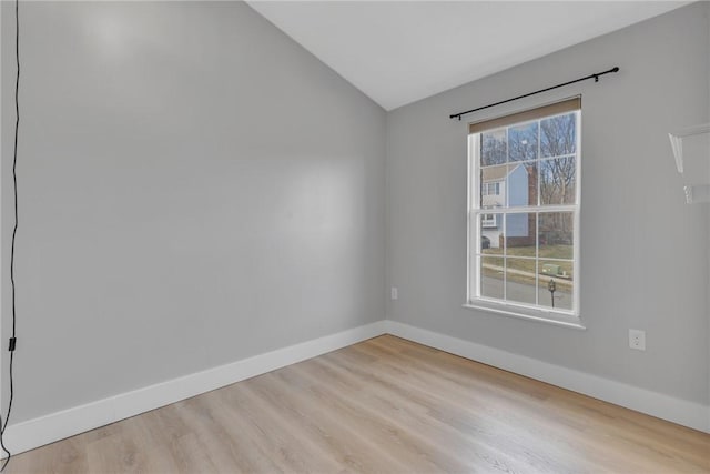 unfurnished room featuring baseboards, wood finished floors, and vaulted ceiling