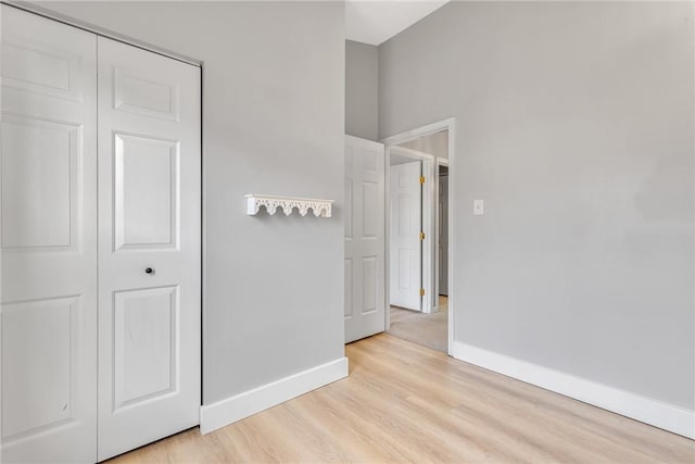 unfurnished bedroom with a closet, baseboards, and light wood finished floors