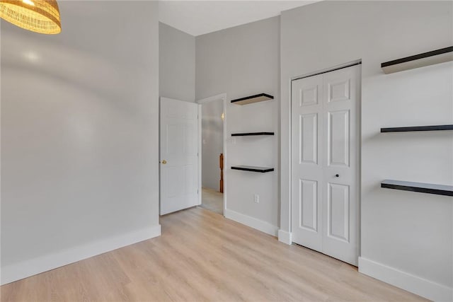 unfurnished bedroom featuring wood finished floors, baseboards, and a closet