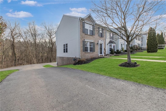 view of front facade with a front lawn, brick siding, and driveway