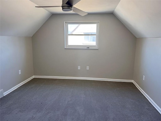 additional living space with vaulted ceiling, baseboards, dark carpet, and ceiling fan