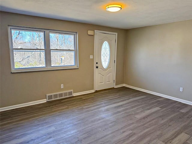 foyer entrance with dark wood-style floors, baseboards, and visible vents