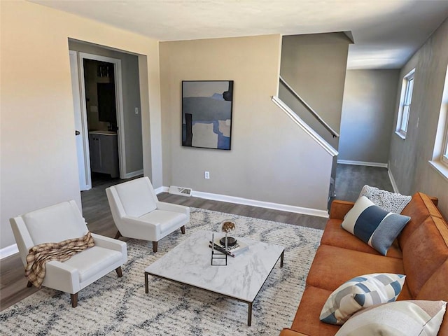 living room featuring visible vents, stairway, baseboards, and wood finished floors