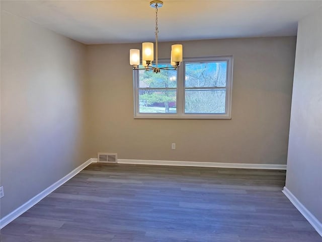 spare room featuring visible vents, baseboards, dark wood finished floors, and a chandelier