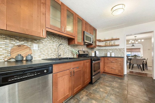 kitchen with dark countertops, a sink, decorative backsplash, appliances with stainless steel finishes, and open shelves