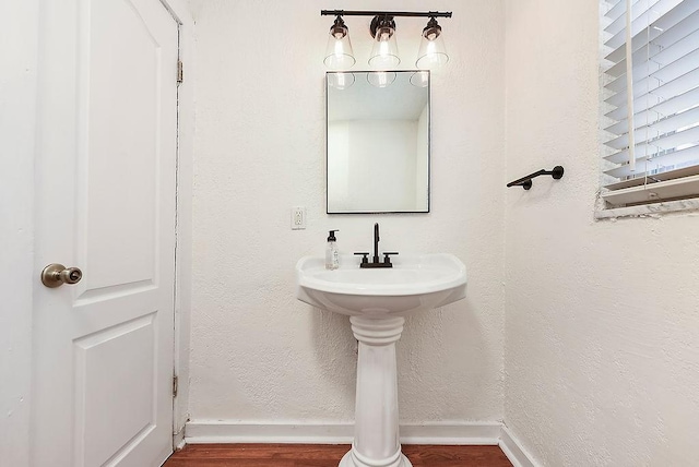 bathroom featuring baseboards, wood finished floors, and a textured wall