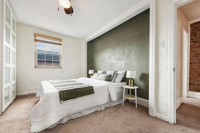 carpeted bedroom featuring a ceiling fan, a textured wall, baseboards, and a textured ceiling